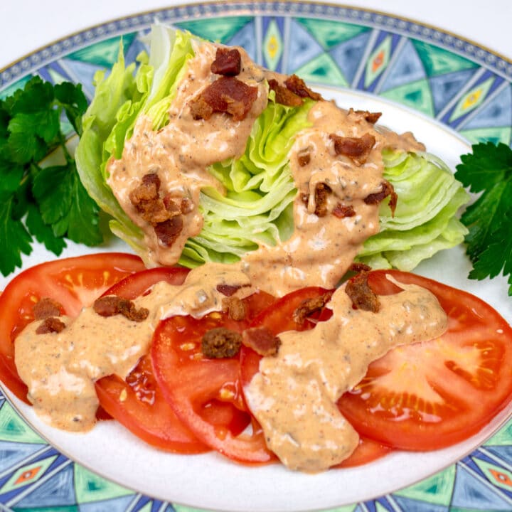 cajun thousand island dressing on lettuce and tomatoes on a decorative plate