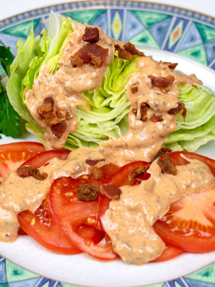 cajun thousand island dressing on lettuce and tomatoes on a decorative plate