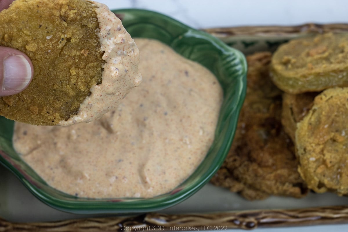 fried green tomato dunked in white remoulade sauce