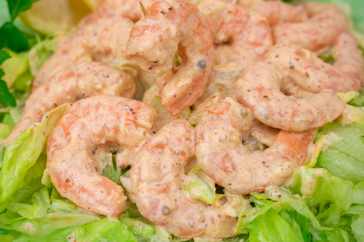 white remoulade sauce mixed with shrimp on a bed of lettuce