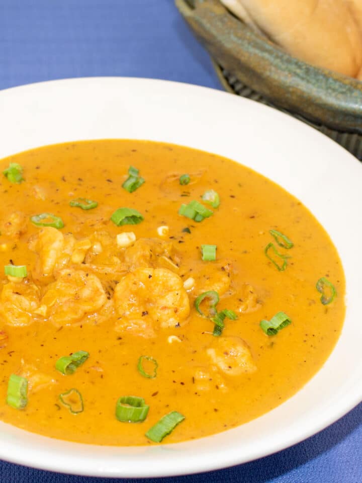 corn and shrimp bisques in a white bowl with french bread on the side