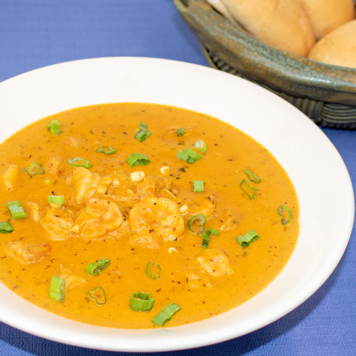 corn and shrimp bisques in a white bowl with french bread on the side