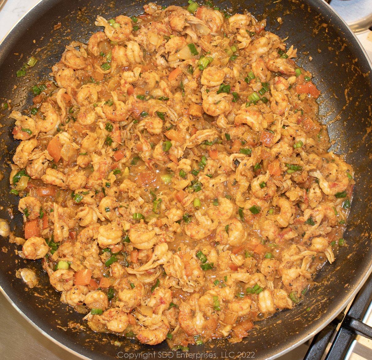 crawfish tails with sautéed vegetables and seasonings in a sauté pan