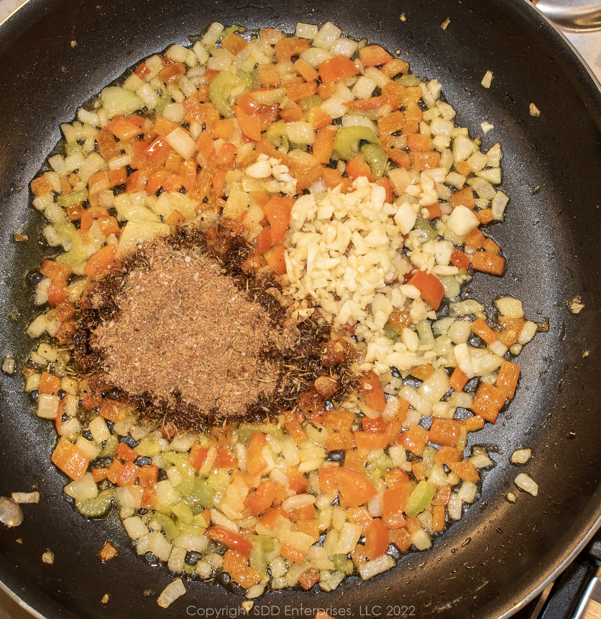 herbs and spices with garlic sautéing with the trinity on a sauté pan