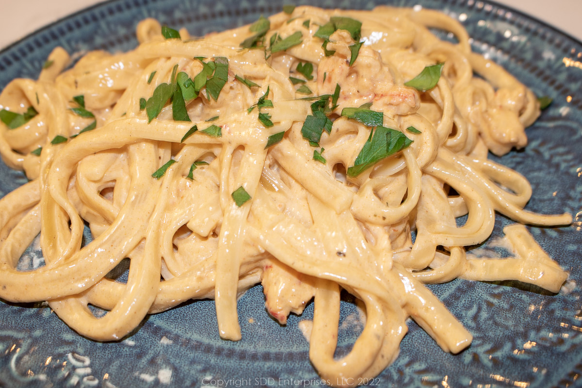 crawfish fettuccini alfredo on a green plate with parsley garnish