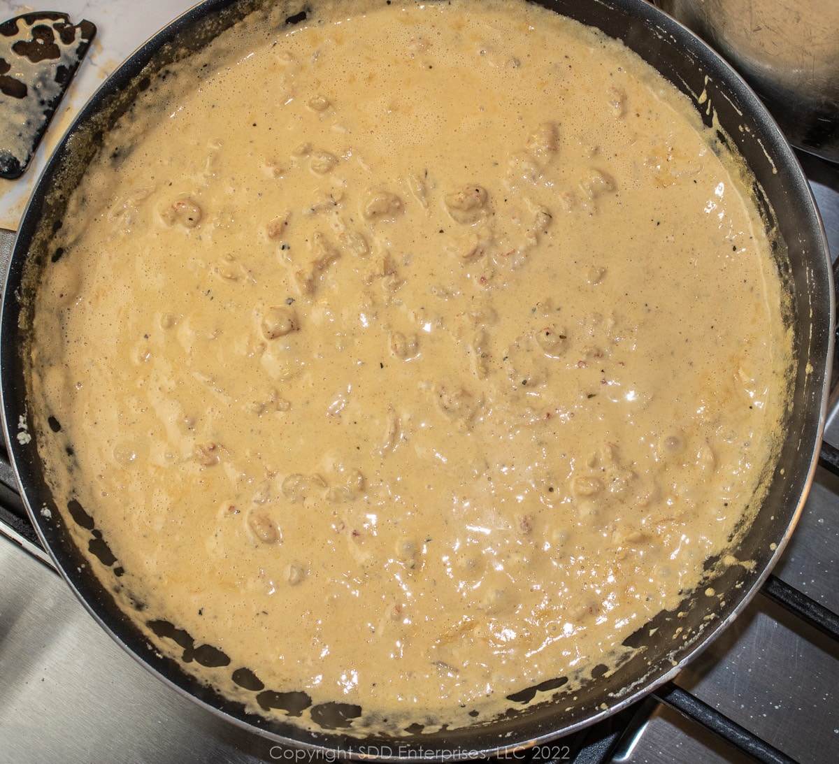 alfredo sauce with crawfish simmering in a sauté pan