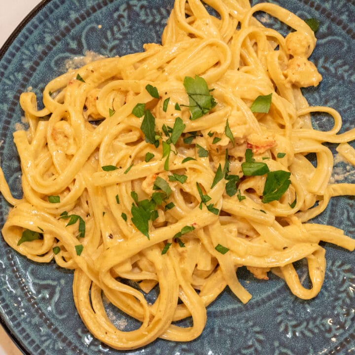 crawfish fettuccini alfredo on a green plate with parsley garnish