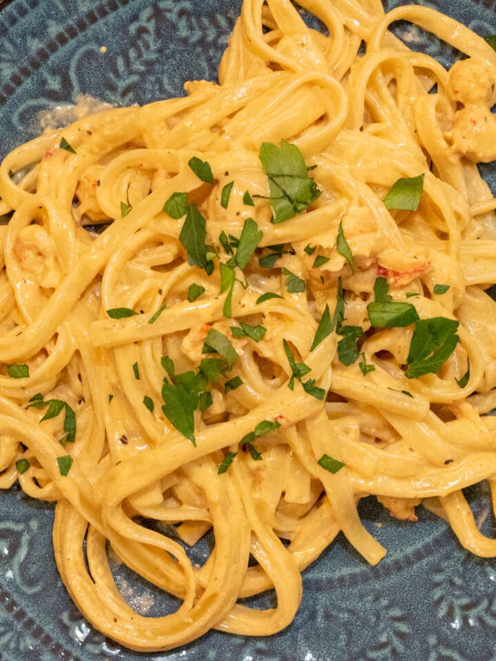 crawfish fettuccini alfredo on a green plate with parsley garnish