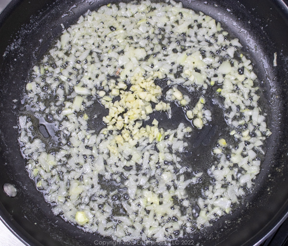 garlic and onions sautéing in butter in a sauté pan