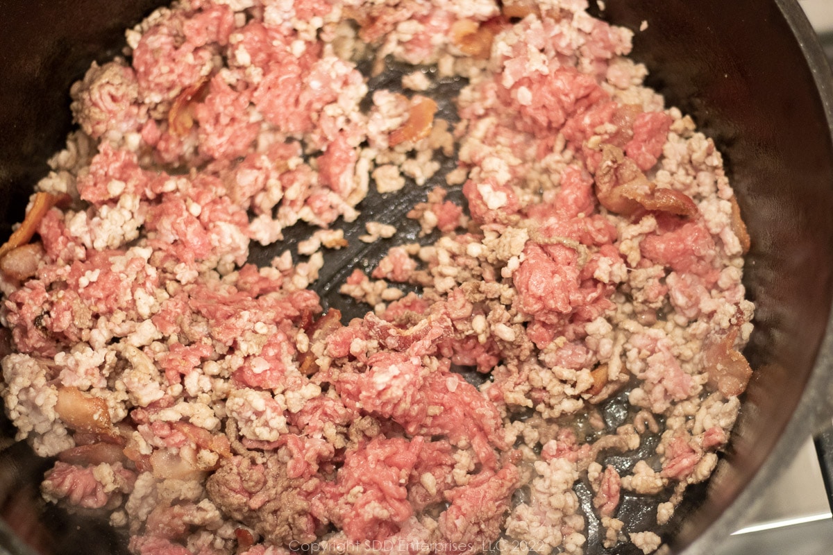ground meats with bacon frying in a Dutch oven