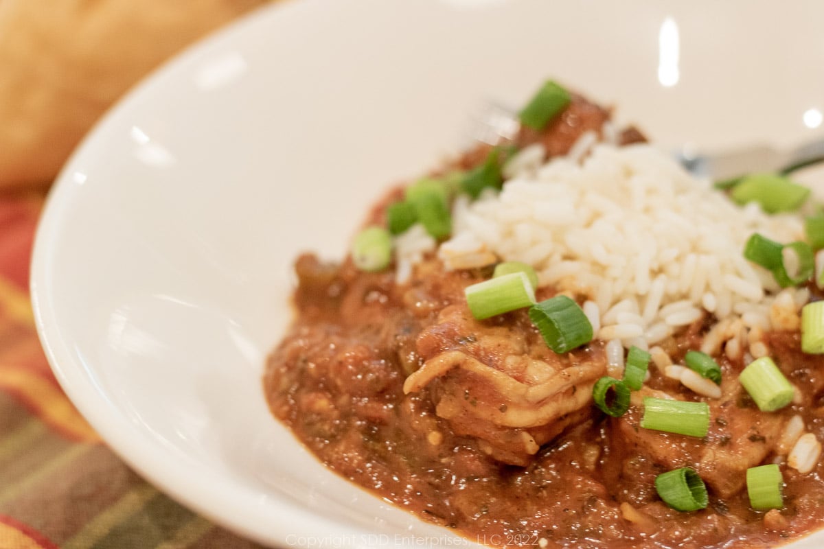 shrimp creole over rice in a white bowl with garnish