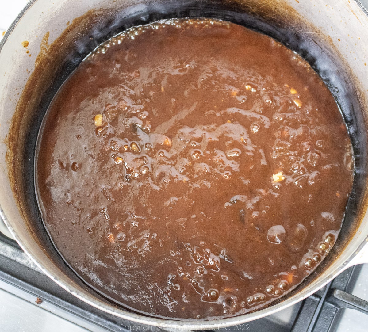 bbq sauce thickening as it simmers in a Dutch oven