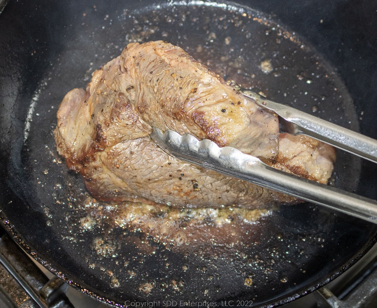 beef chuck roast being seared in a Dutch oven