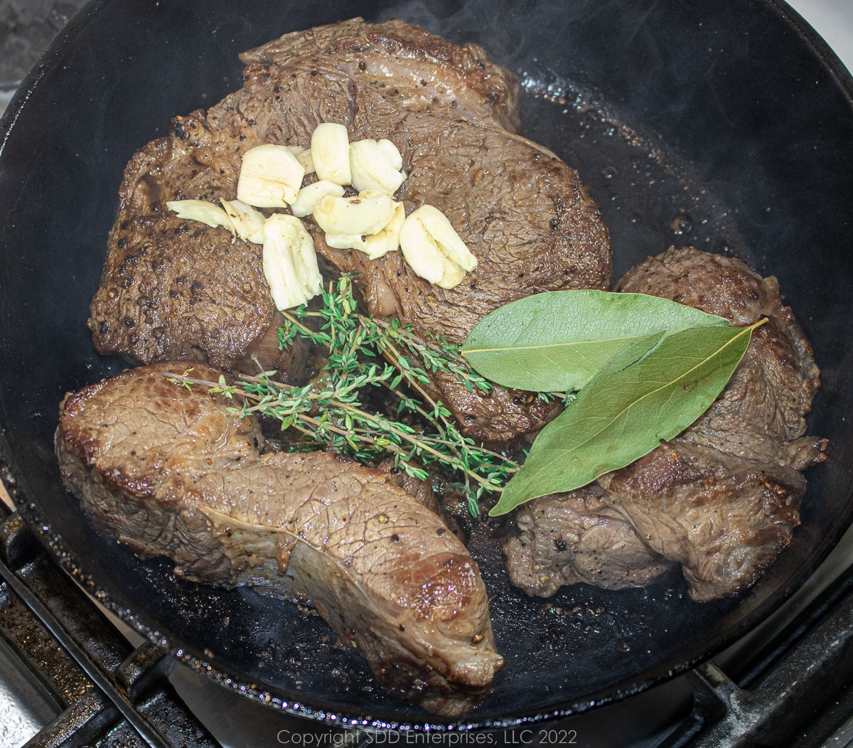 seasonings added to seared beef in a Dutch oven