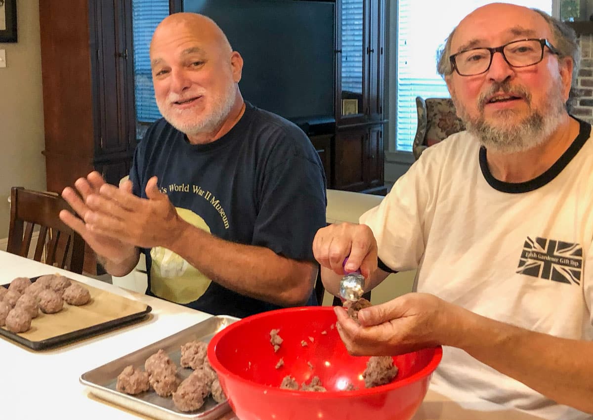 Two guys rolling and forming meatballs