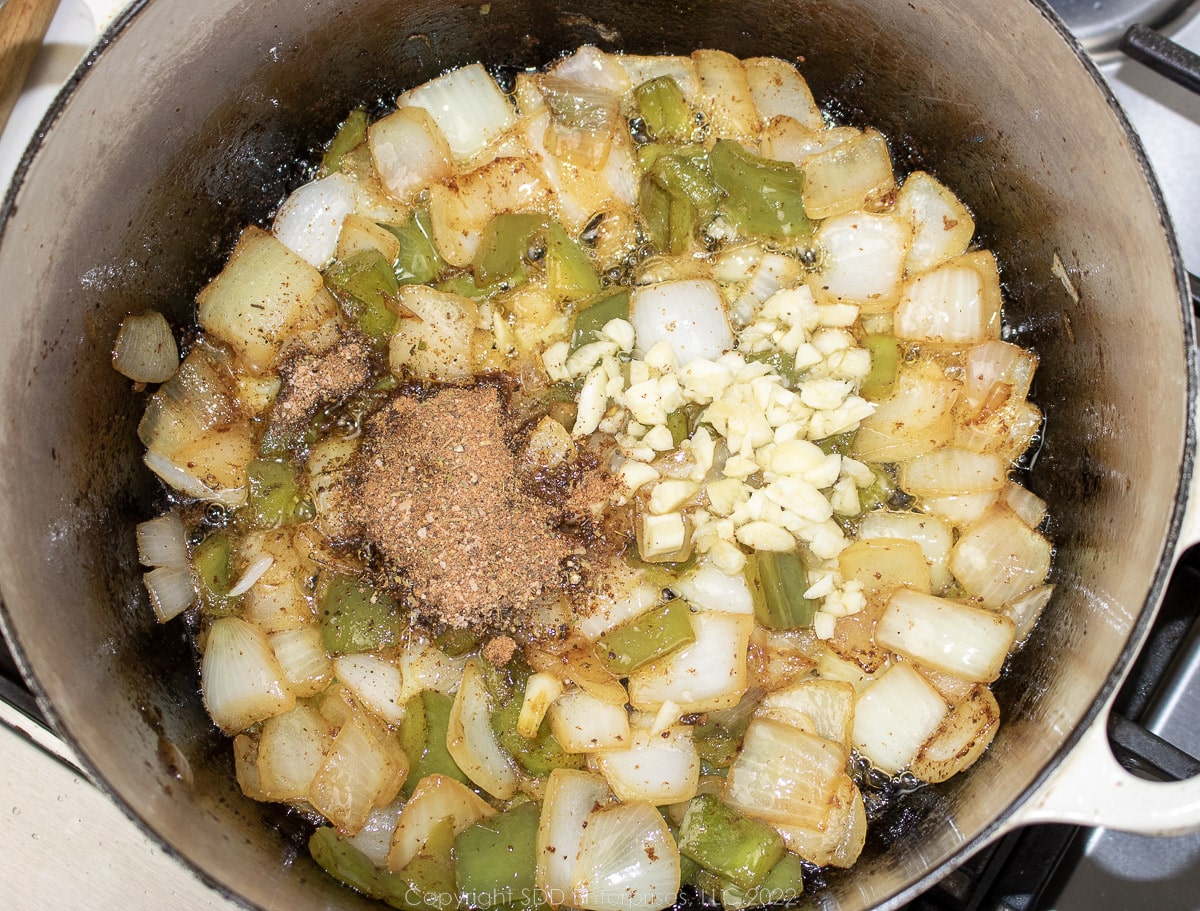 garlic and herbs added to the trinity in a Dutch oven