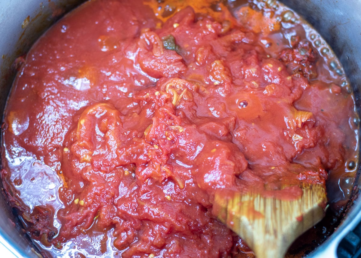 whole tomatoes added to simmering vegetables in a Dutch oven