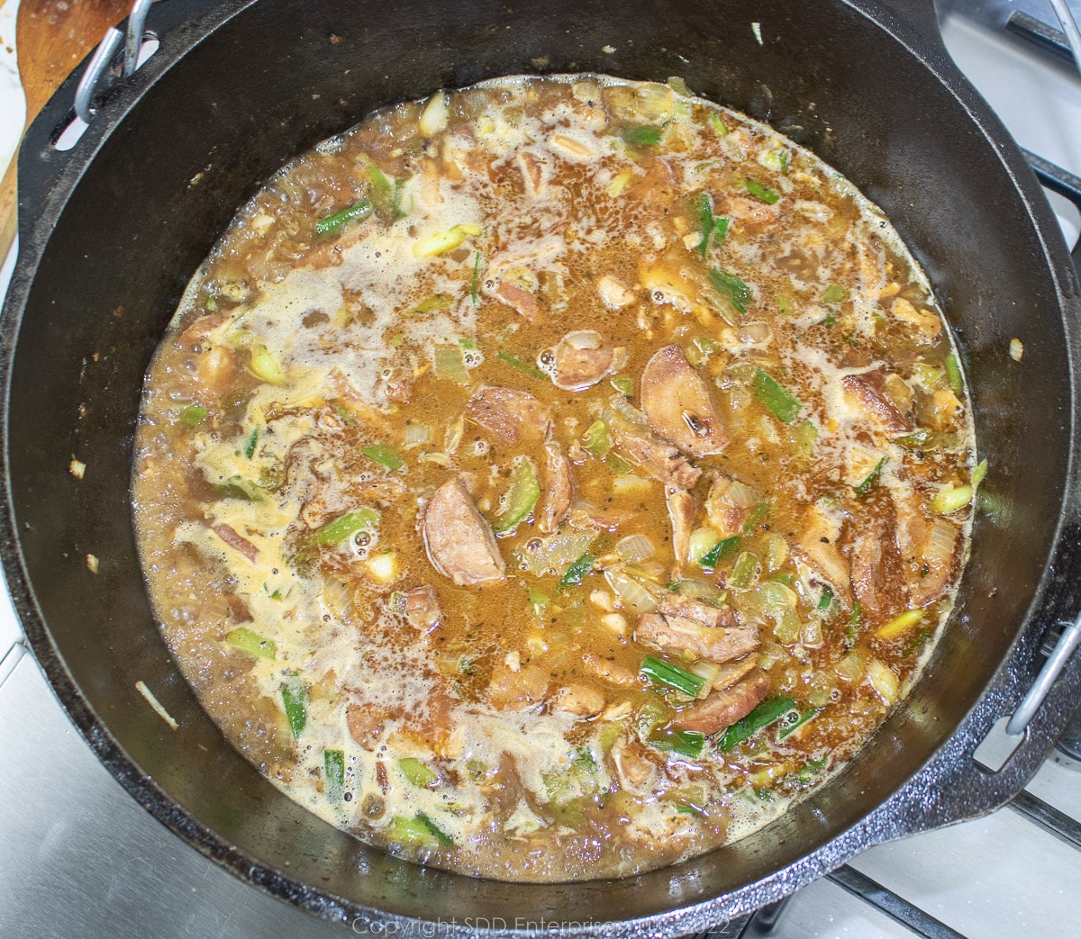 stock with vegetables and meat simmering in a Dutch oven