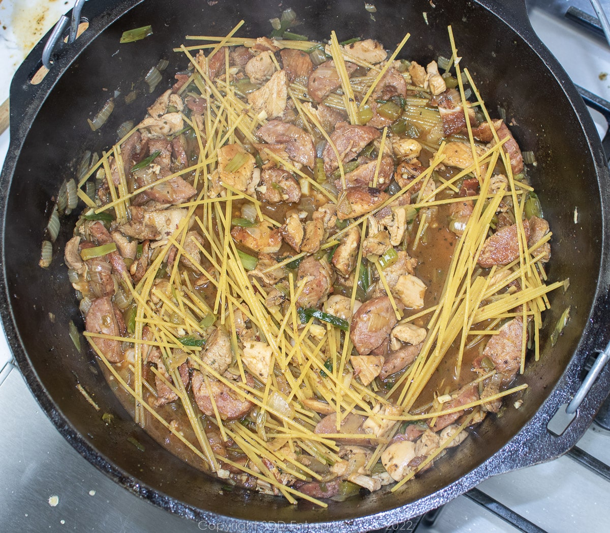 dry spaghetti mixed with stock in a Dutch oven.