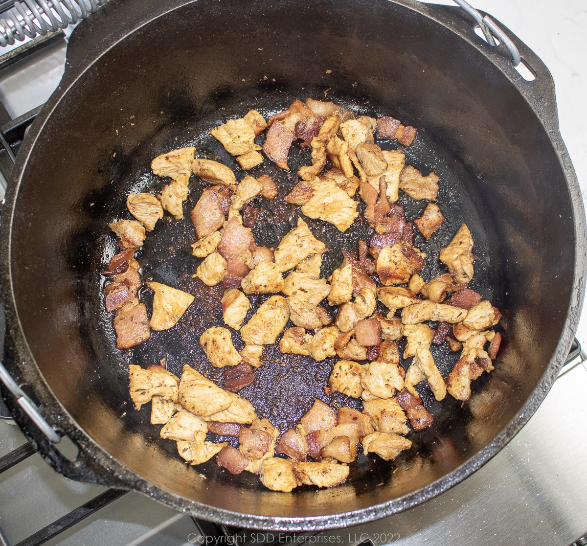 pieces of pork frying in a Dutch oven