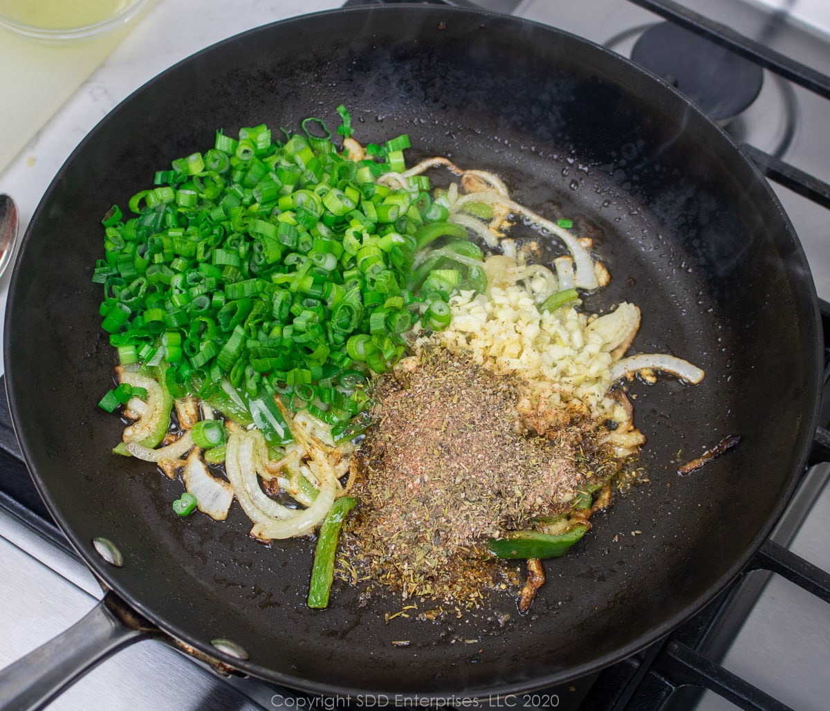 aromatics added to sautéed onions and peppers in a skillet