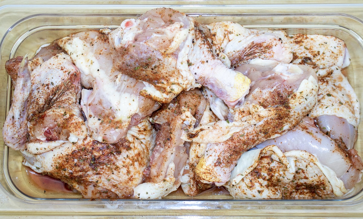 cut up chicken with seasoning on a prep platter