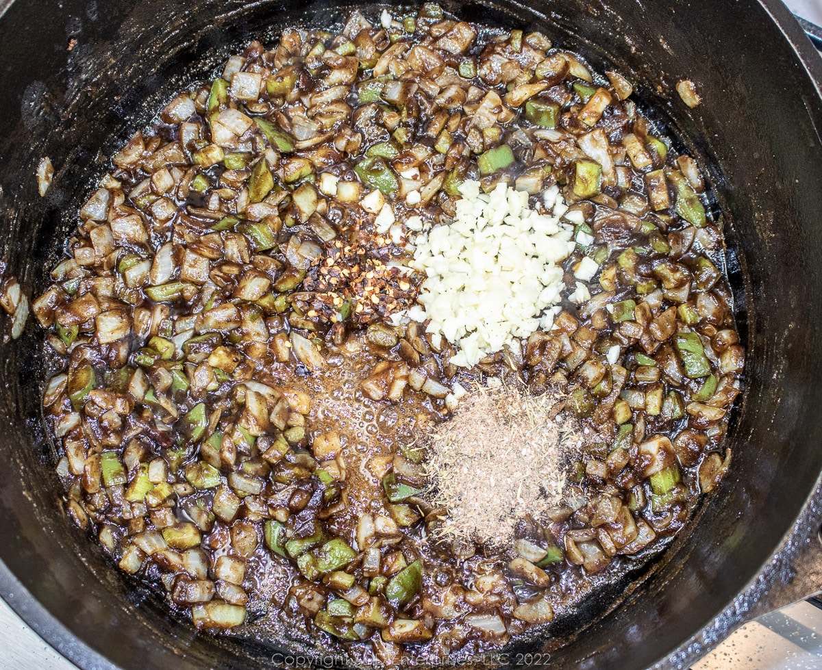 garlic and seasonings added to the trinity in a Dutch oven