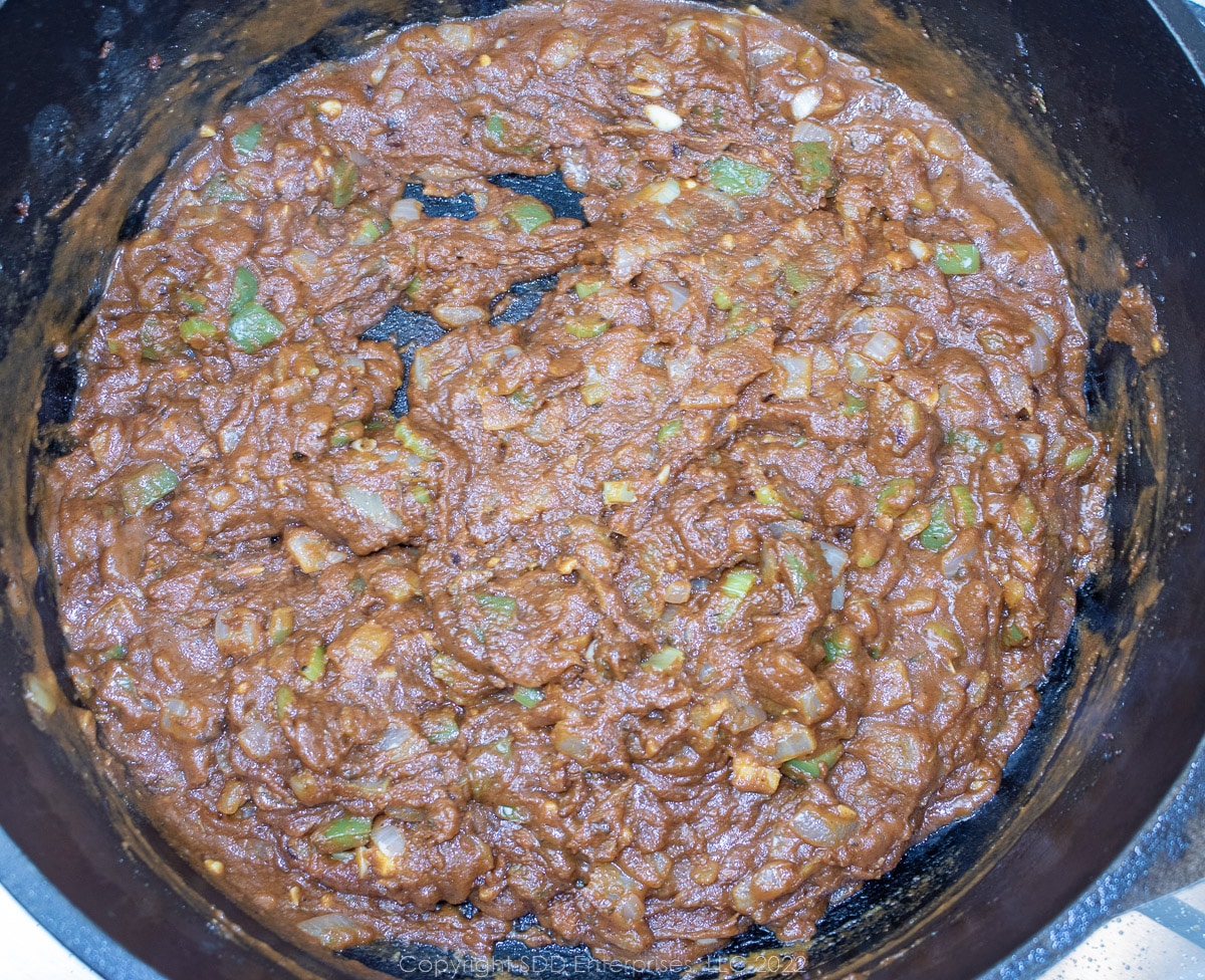 wine mixed into tomato sauce and trinity in a Dutch oven