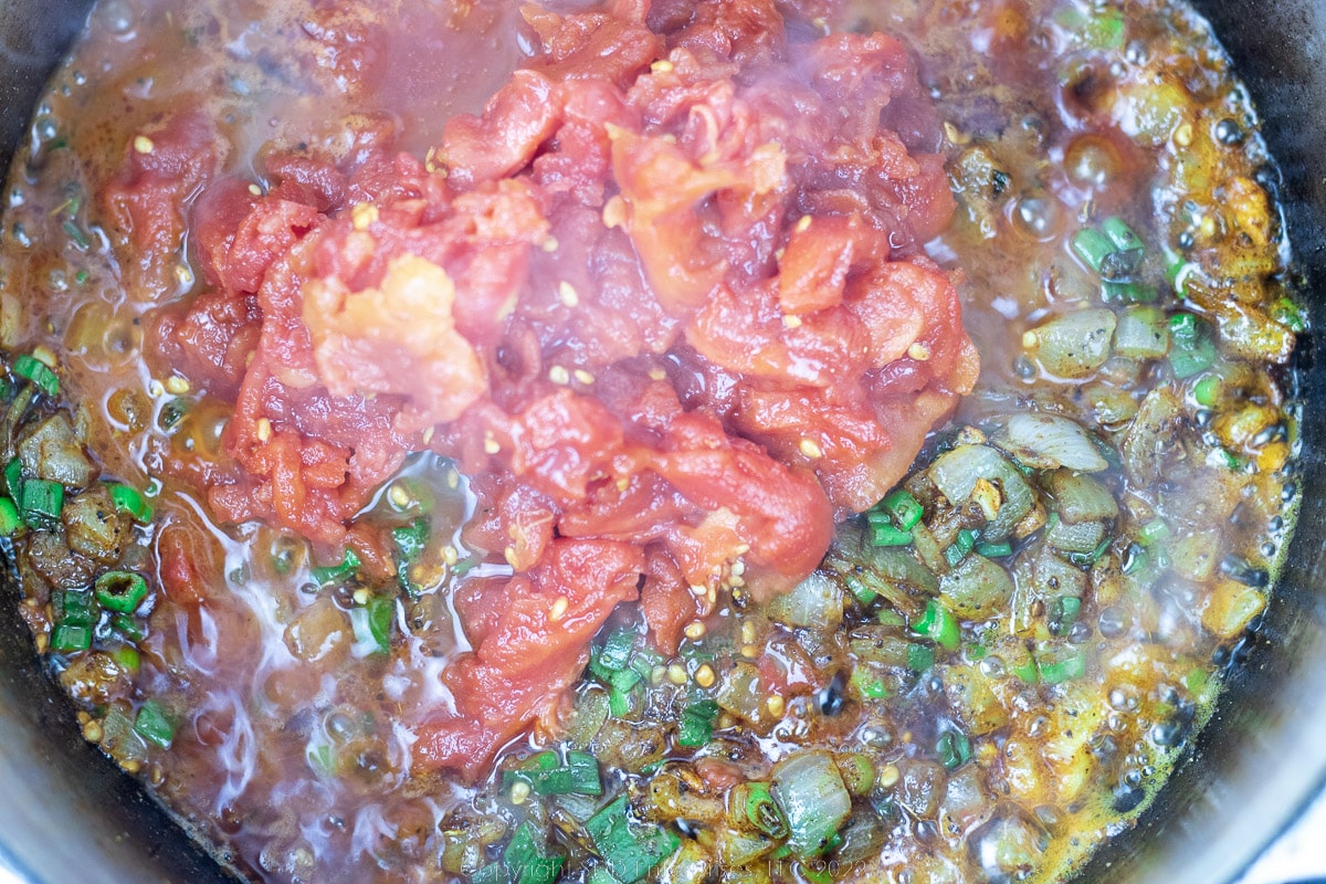 whole tomatoes added to sautéing vegetables in a Dutch oven