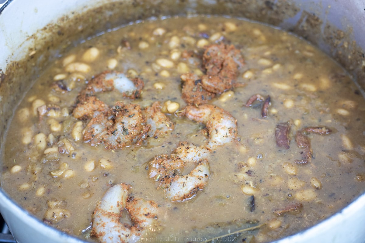shrimp and white beans simmering in a Dutch oven