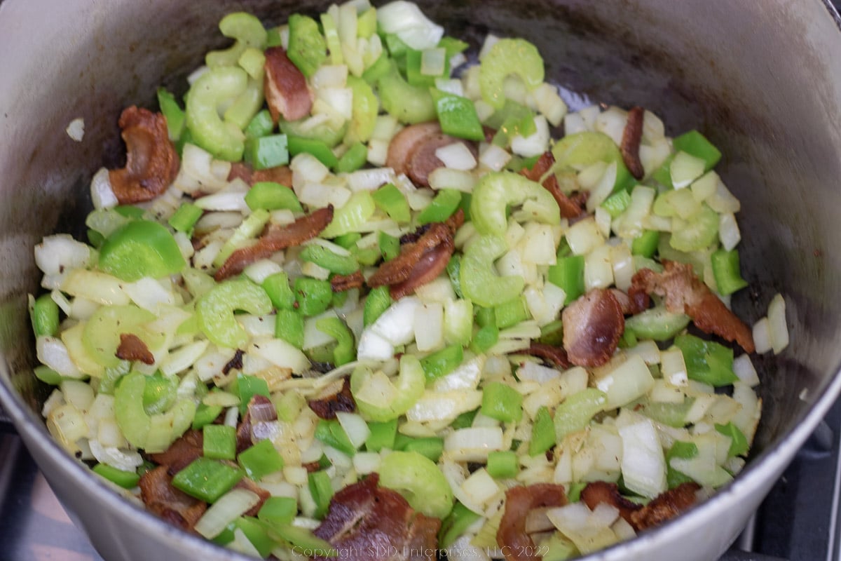 onions, bell peppers, and celery added to bacon drippings in a Dutch oven