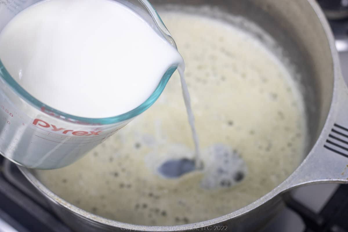 milk being added to roux in a Dutch oven