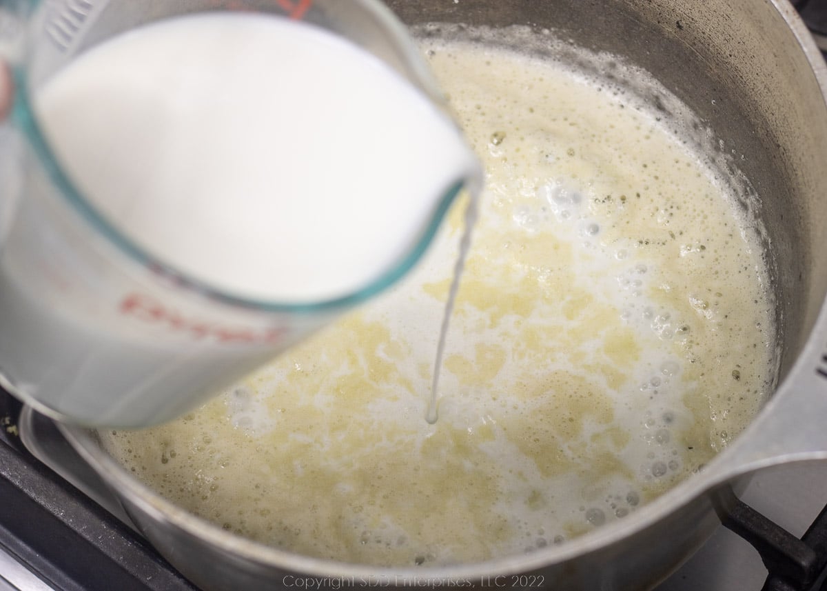 milk being added to roux in a Dutch oven