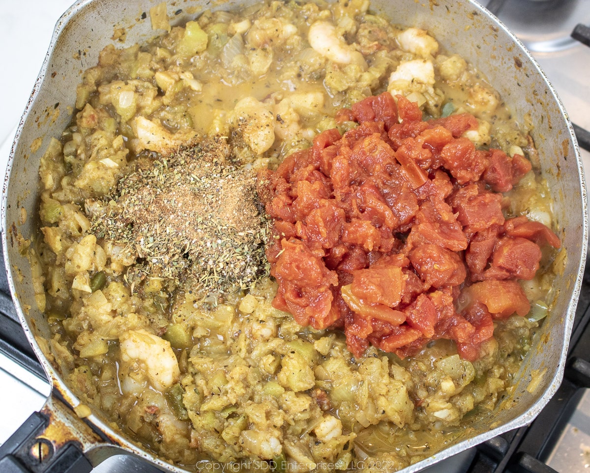 tomatoes and seasonings added to simmering vegetables and shrimp