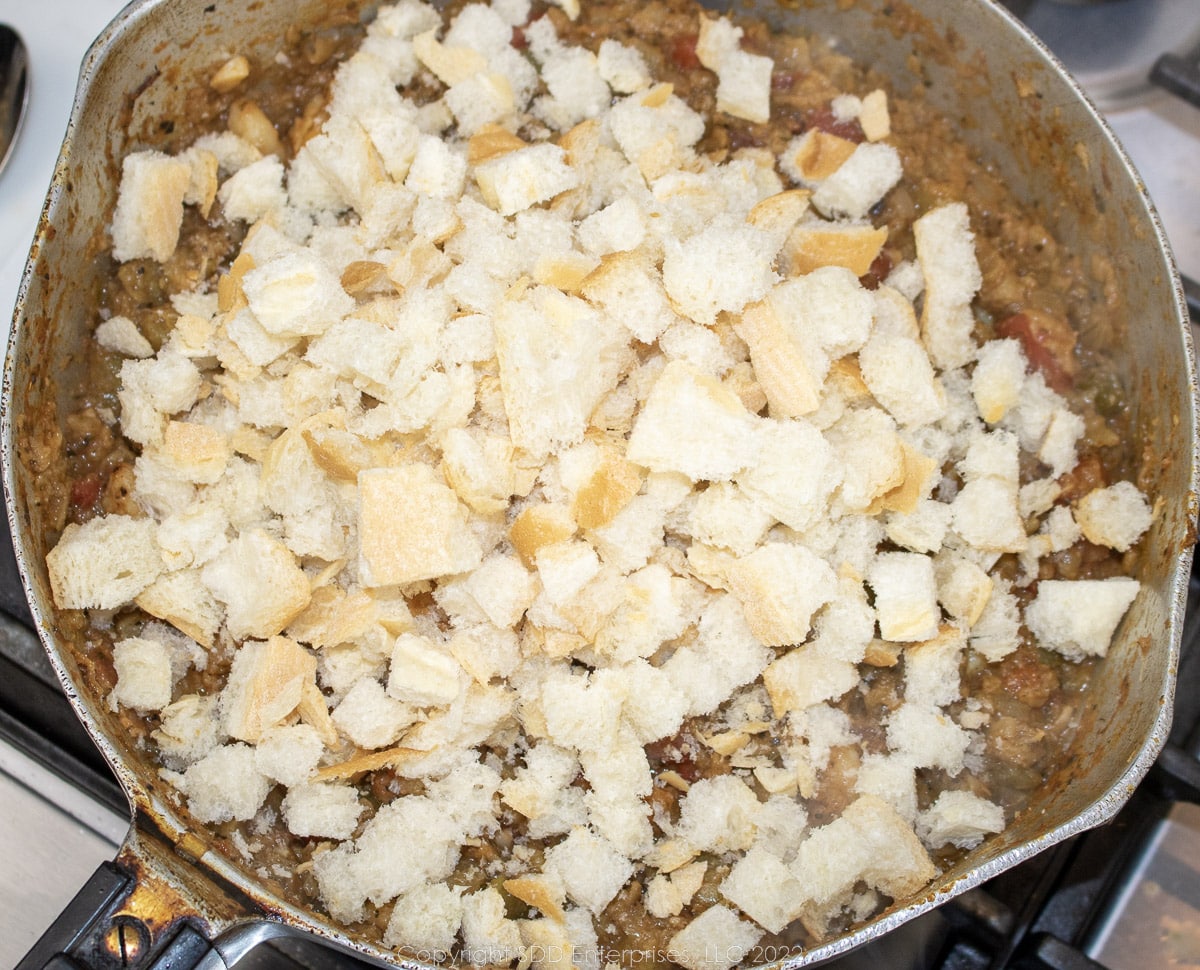 stale bread cubes added to simmering vegetables and shrimp in a frying a pan