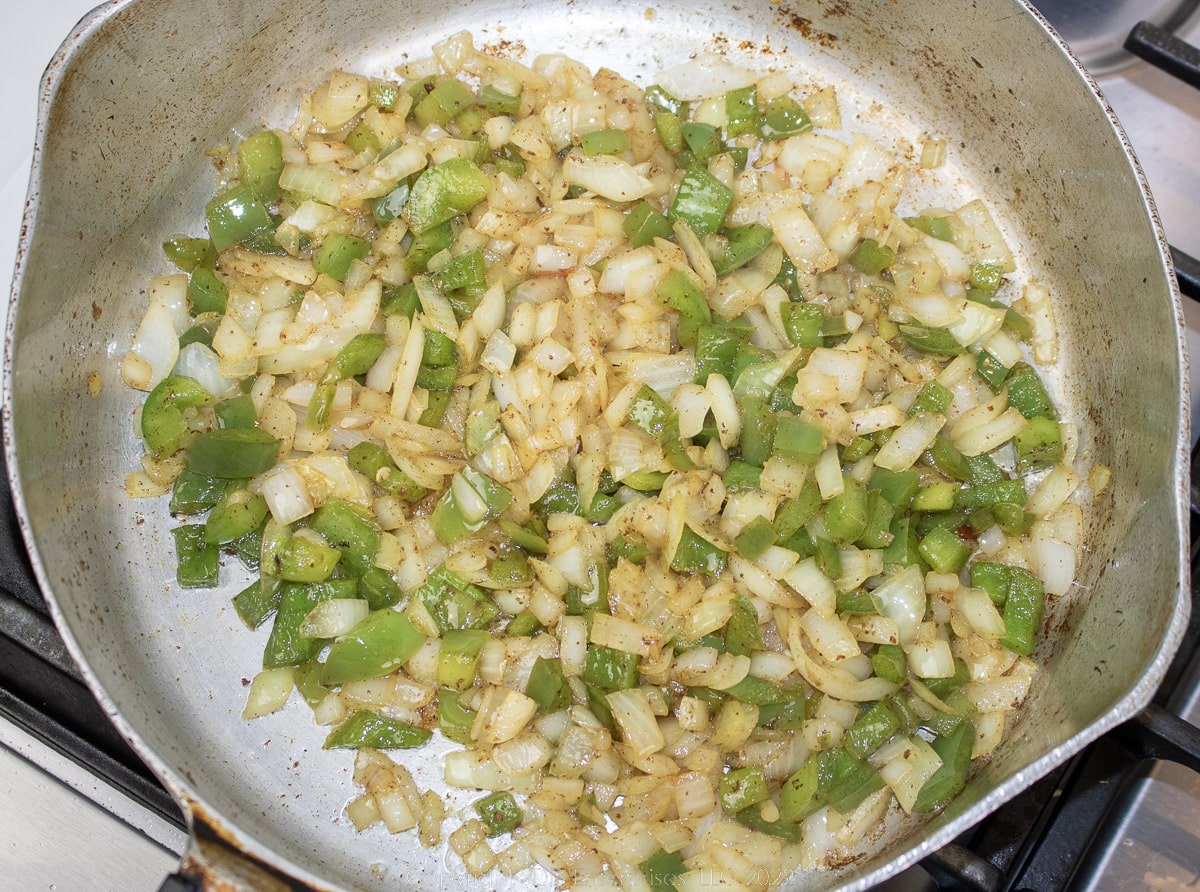 onions and bell peppers frying on bacon dripping