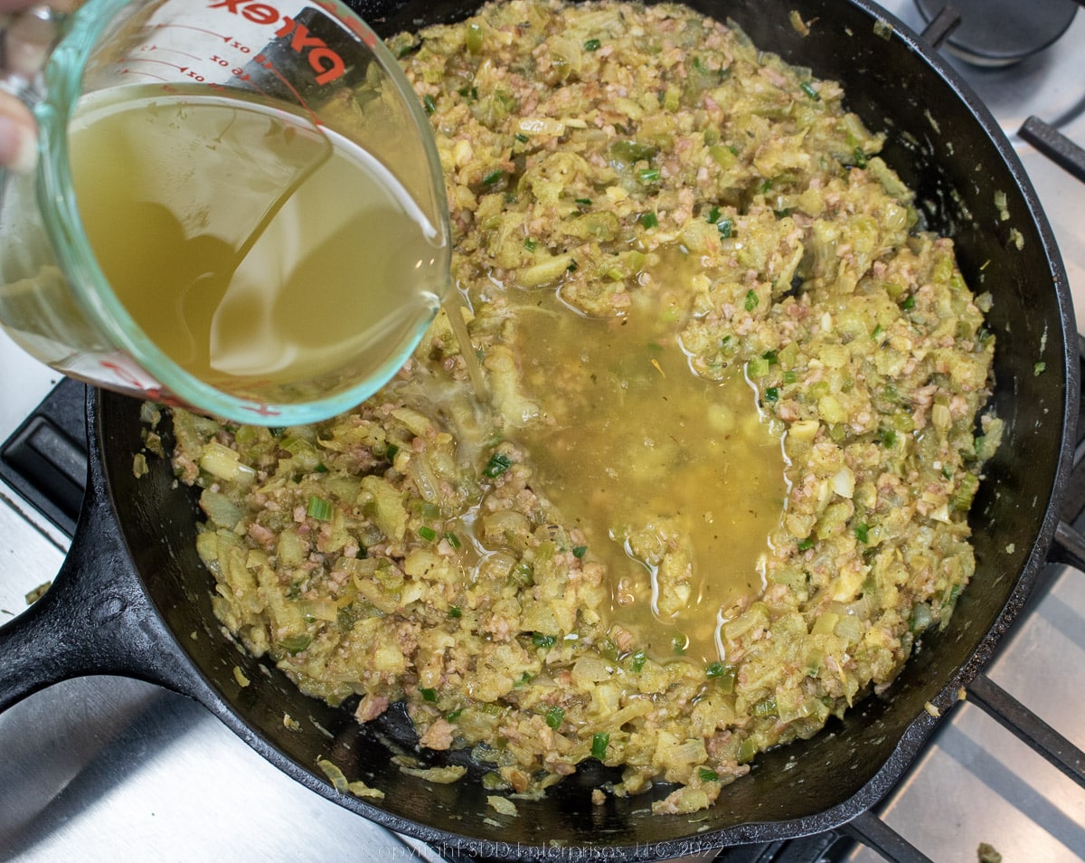 stock being added to ham and vegetables in a cast iron skillet