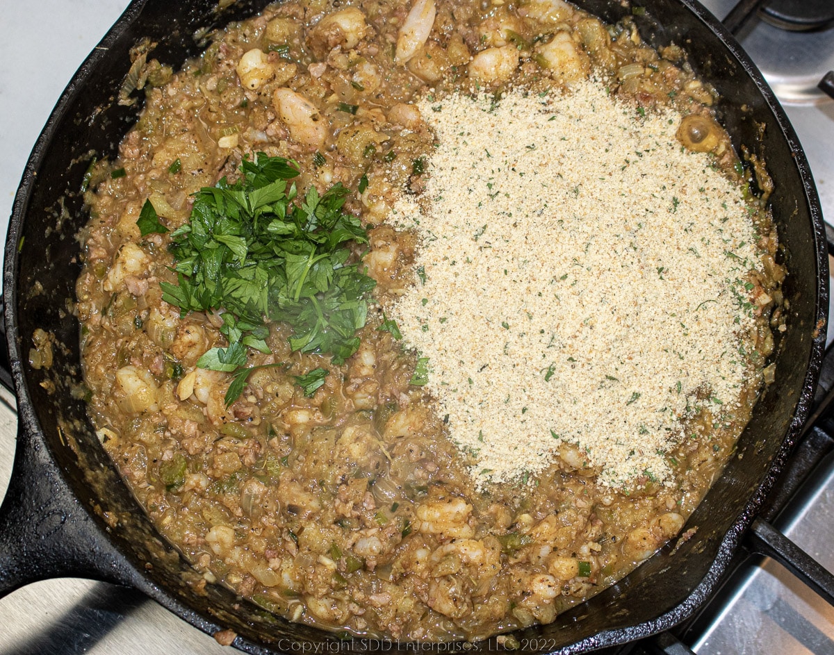 breadcrumbs and parsley added to filling mixture in a cast iron skillet