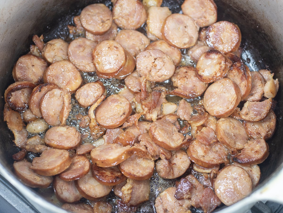 sausage medallions frying in a Dutch oven 