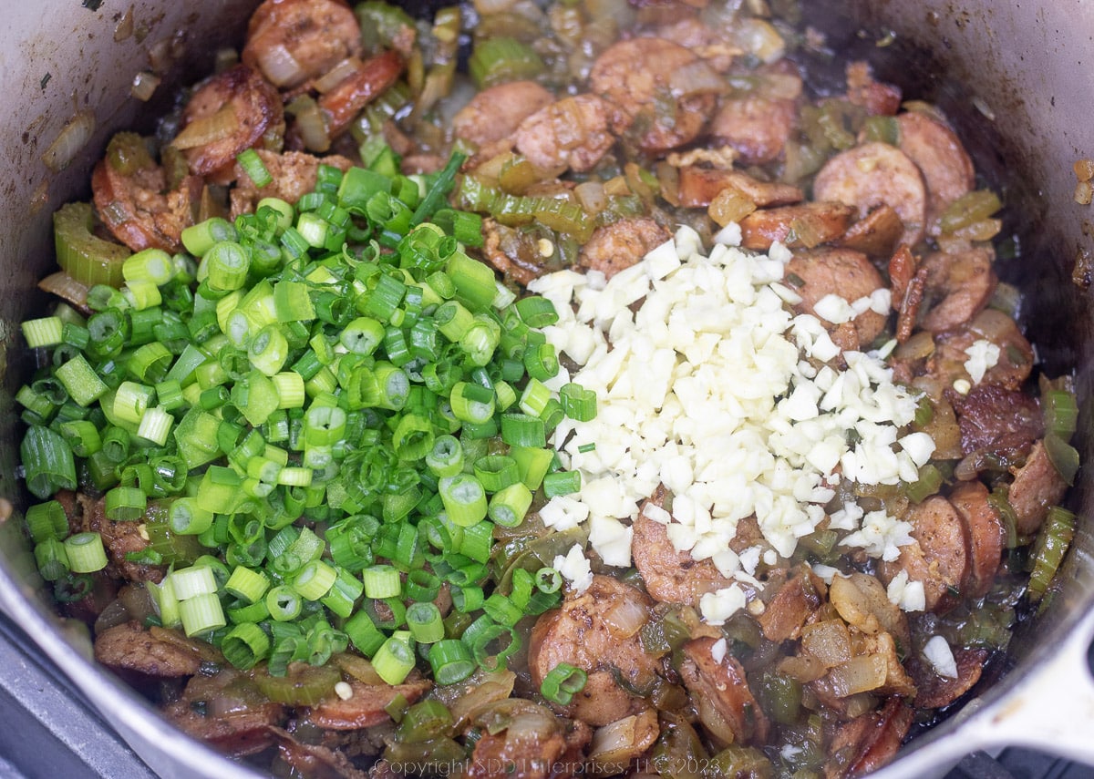 green onions and garlic added to a Dutch oven with sausage