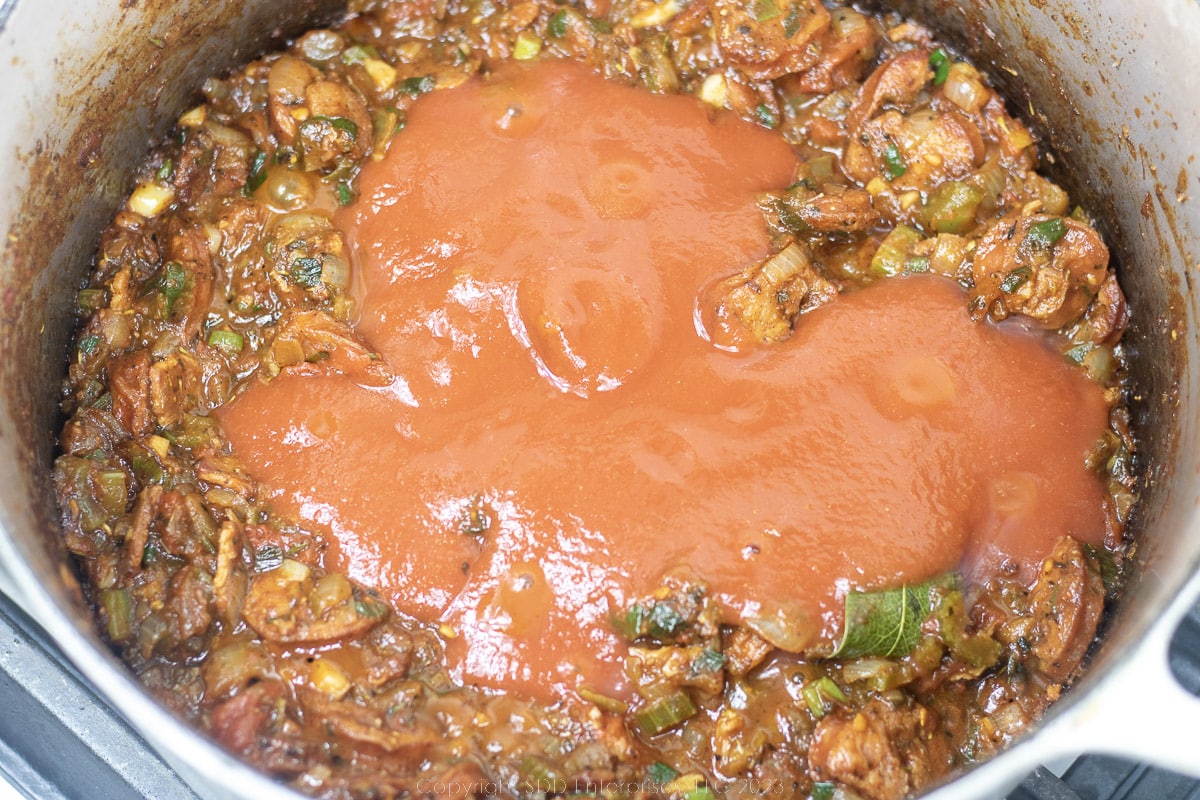 tomato sauce mixed into jamabalaya base in a Dutch oven