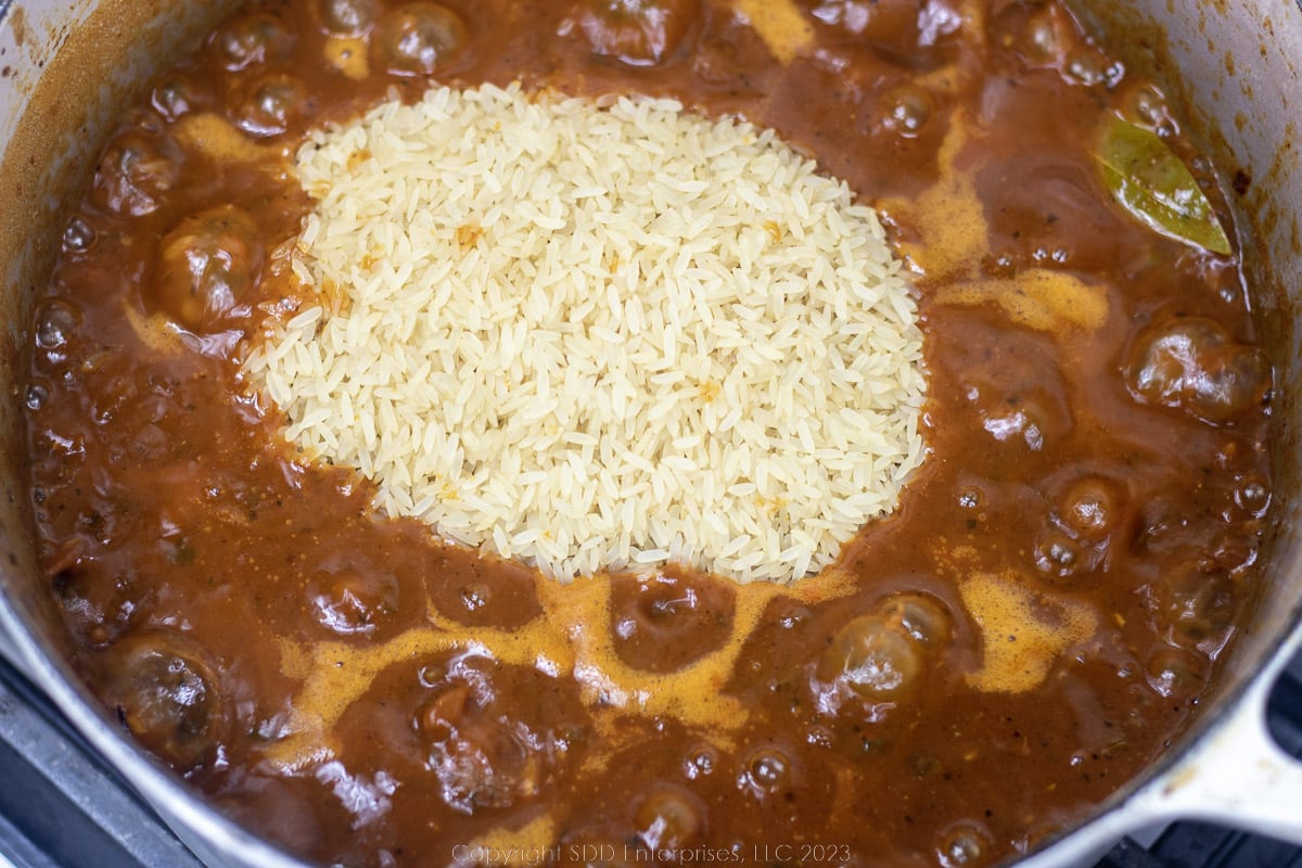 uncooked rice added to simmering mixture in a Dutch oven