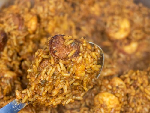 Creole Jambalaya on a serving spoon over a Dutch oven