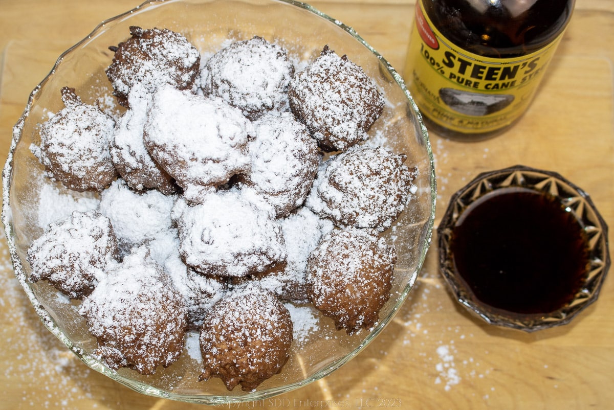 a bowl of calas with powdered sugar and cane syrup