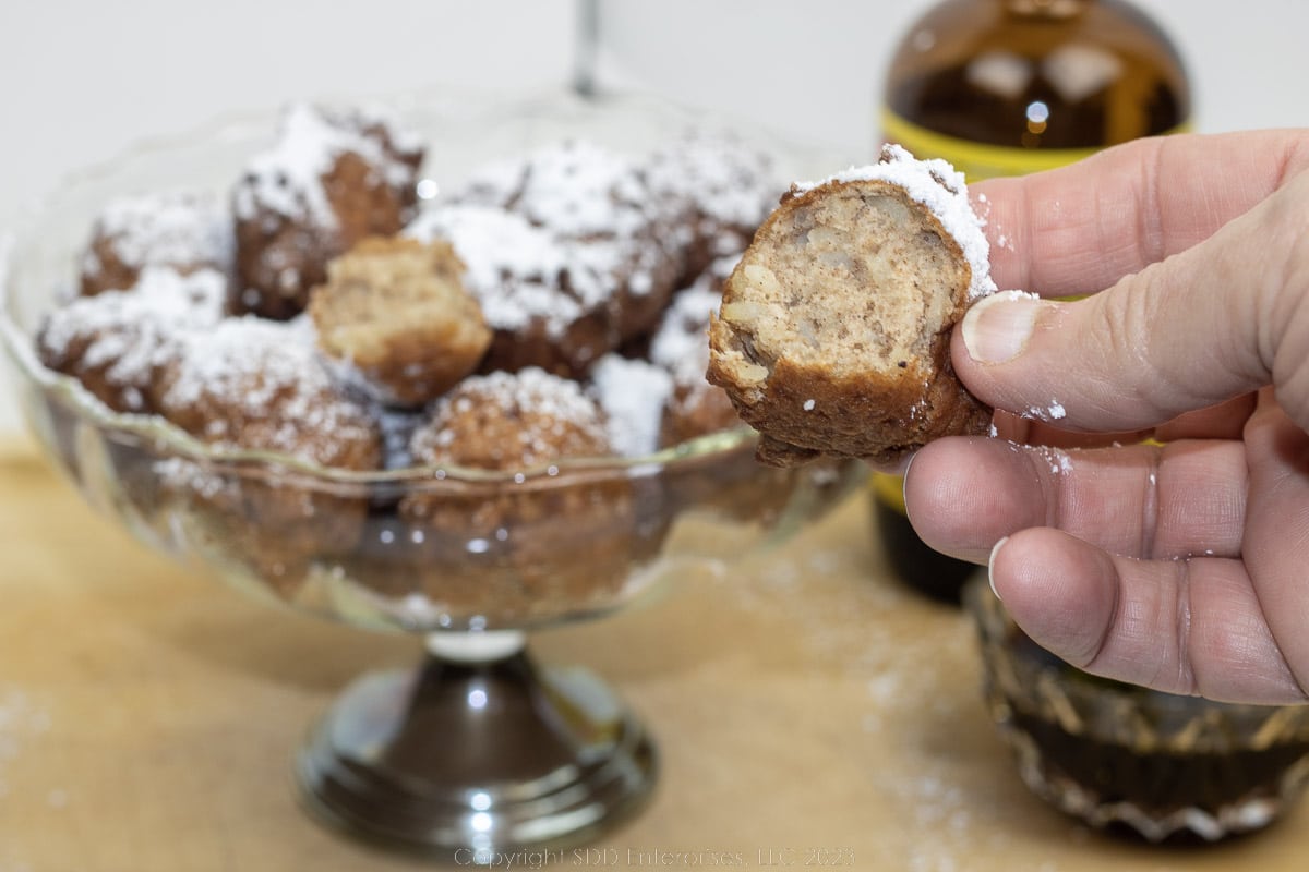calas with powdered sugar and cane syrup in a serving bowl.
