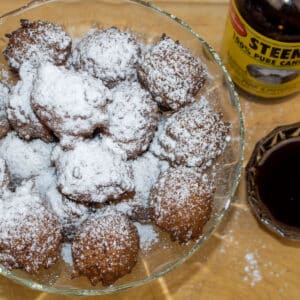 rice calas in a serving bowl with powdered sugar and cane syrup