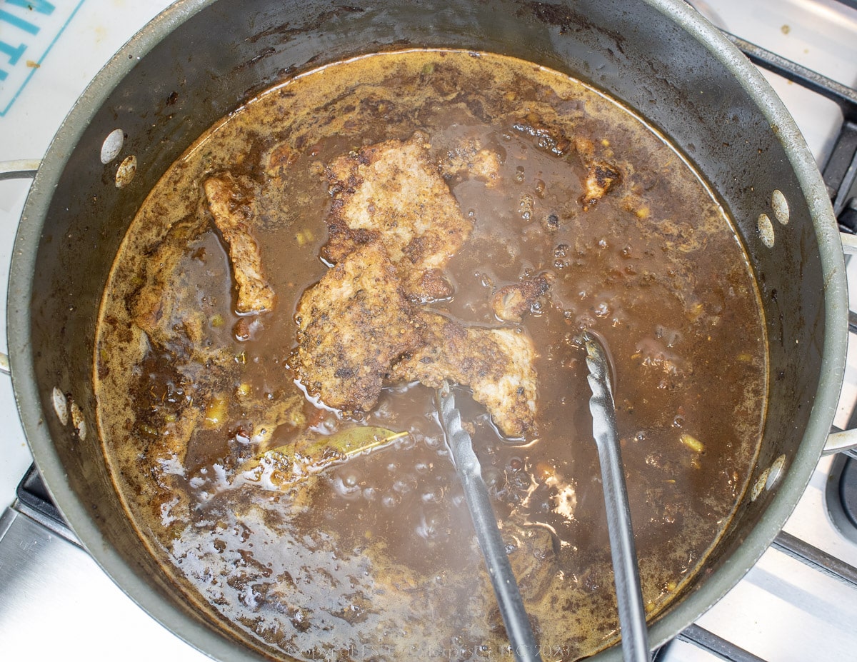 browned meat added to a sauce in a Dutch oven