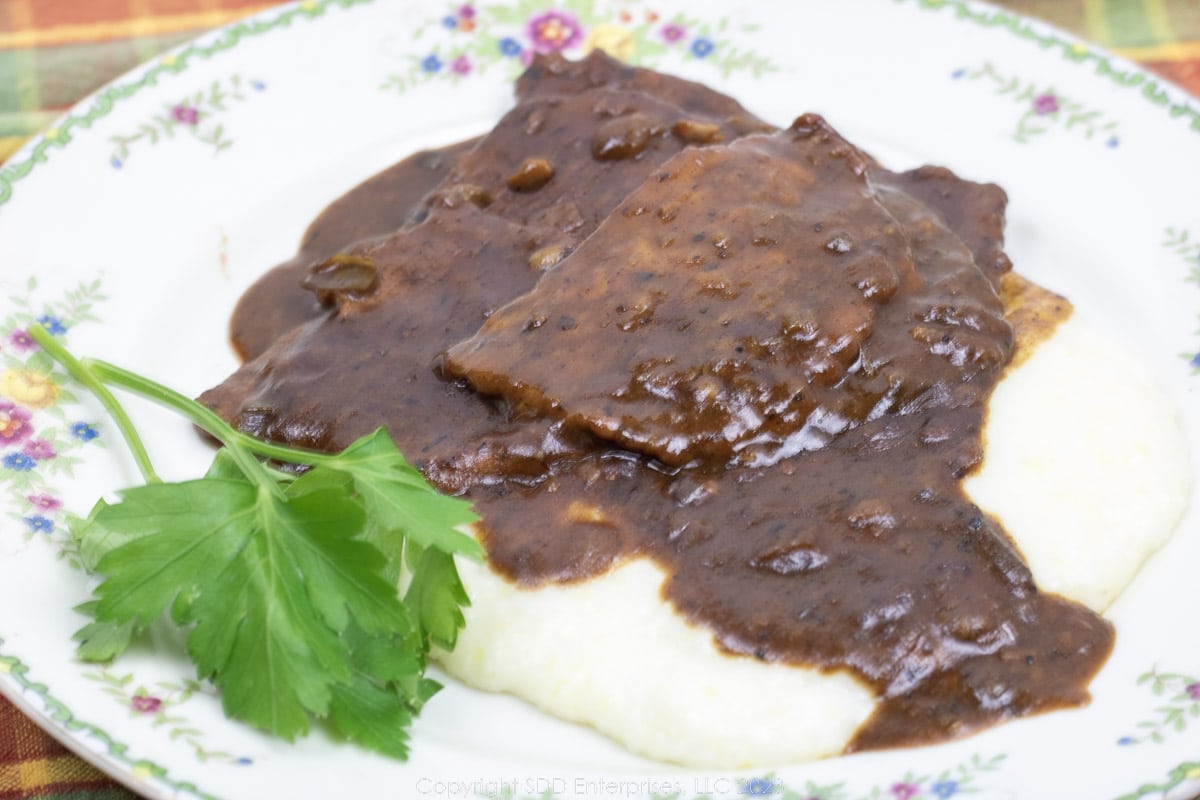 grillades with grits on a plate with garnish