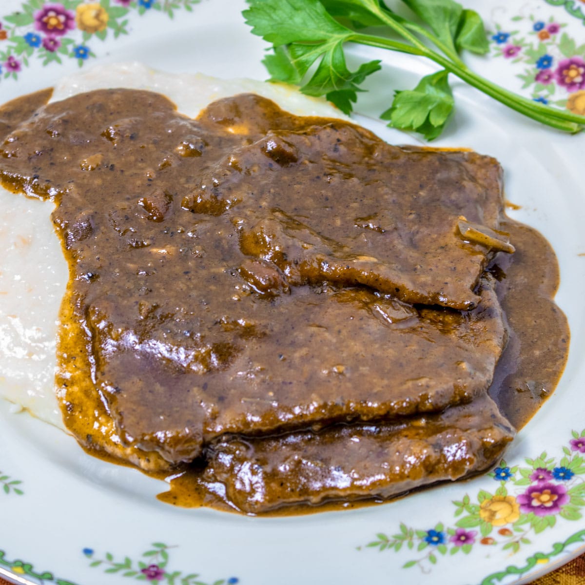 grillades with gravy over grits on a plate