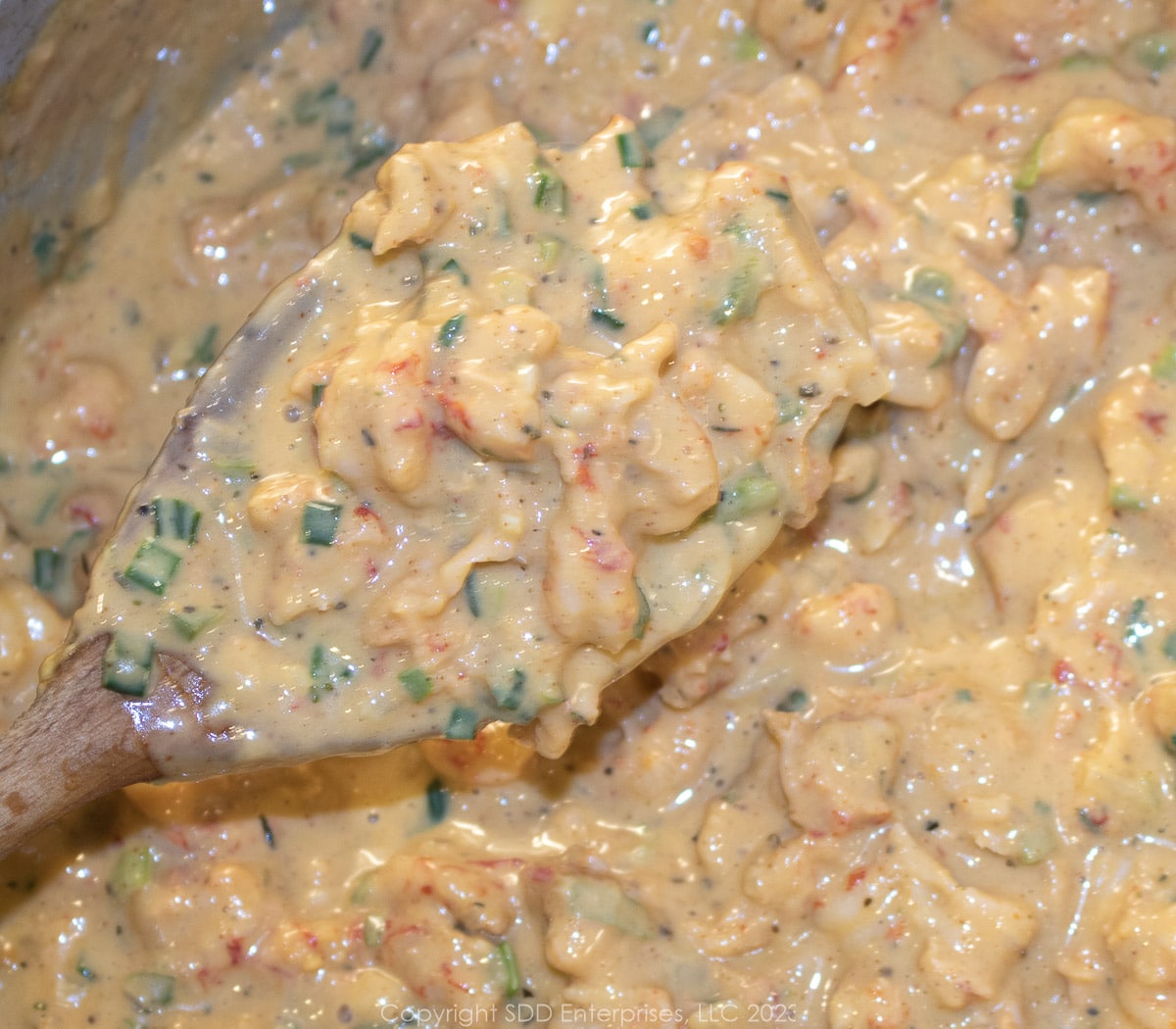 crawfish tails and sherry added to cheese sauce in a frying pan